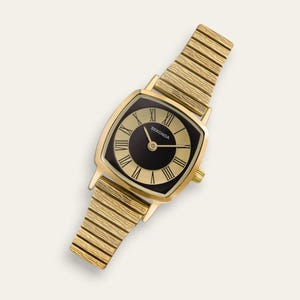 May include: A gold-toned Sekonda wristwatch with a square face and a black dial. The watch features gold Roman numerals and hands, and a gold-colored, expandable band. The watch is set against a white background.