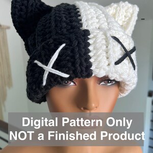 Puede incluir: Un gorro de ganchillo hecho a mano en blanco y negro, con orejas de gato y detalles de 'X' cosidos. El gorro está dividido por la mitad, con un lado negro y el otro blanco. El texto de la imagen dice: Digital Pattern Only NOT a Finished Product.