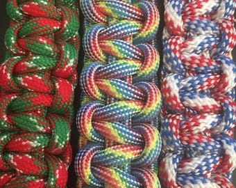 May include: Close-up of three braided rope sections in vibrant colors. One section features red and green, another displays a rainbow of hues, and the third combines red, white, and blue. The braided design is tightly woven.