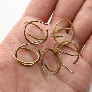 May include: Four pairs of gold hoop earrings with a double ring design. The earrings are made of brass and have a silver post.