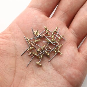Può includere: Un mucchio di perni per orecchini in argento e oro con cime a forma di stella.