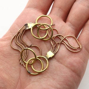 May include: Gold tone earrings with a chain tassel and three interlocking rings.
