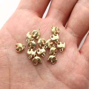 Puede incluir: Un montón de abalorios de elefante de metal dorado con un bucle para sujetar a joyas u otras manualidades.