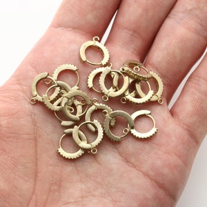 Puede incluir: Un montón de hallazgos de pendientes de aro de color dorado con un borde texturizado.