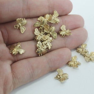 May include: A collection of gold-toned metal bee charms. The charms are detailed and have a realistic bee design.