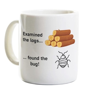 May include: White ceramic mug with a handle featuring the text "Examined the logs... ... found the bug!" with illustrations of logs and a bug. The mug is designed for beverages.