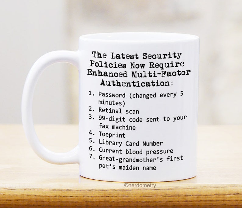 Op de afbeelding: Een witte keramische koffiemok met zwarte tekst die luidt "The Latest Security Policies Now Require Enhanced Multi-Factor Authentication: 1. Password (changed every 5 minutes) 2. Retinal scan 3. 99-digit code sent to your fax machine 4. Toeprint 5. Library Card Number 6. Current blood pressure 7. Great-grandmother's first pet's maiden name" en de tekst "@nerdometry" onderaan.