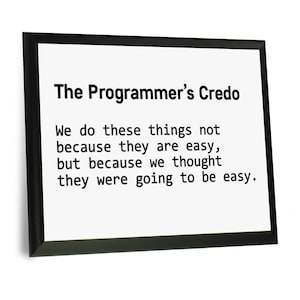 May include: A black framed print with the text "The Programmer's Credo" and a quote about the challenges of programming. The quote reads: "We do these things not because they are easy, but because we thought they were going to be easy."