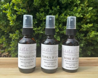 May include: Three brown glass bottles with black spray tops and white labels. The labels read "Smoked Oud", "Tonka & Oud", and "Rose & Oud". Each bottle is labeled "Room and Linen Spray" and "2 oz - 57 g".