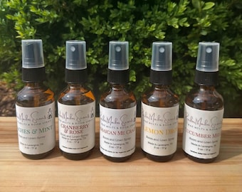 May include: Five small brown glass bottles with white labels and black spray tops. The labels have the text "Robin Makers Scents" and the names of different scents: "Peaches & Mint", "Cranberry & Rose", "Jamaican Me Crazy", "Lemon Drop", and "Cucumber Melon".