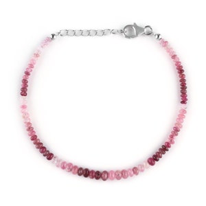 May include: A delicate bracelet made with pink and red gemstone beads. The bracelet has a silver clasp and chain.