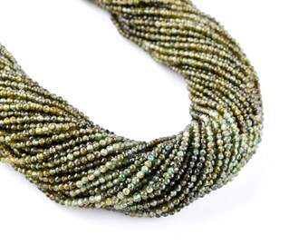May include: A strand of green gemstone beads, each bead is faceted and has a slightly irregular shape.
