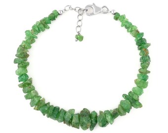 Puede incluir: Un brazalete de cadena de plata con cierre de broche, que presenta una fila de cuentas de piedras preciosas verdes. Las cuentas son de forma irregular y tienen una textura rugosa y natural.