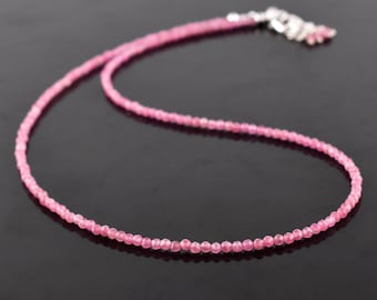 May include: A delicate pink gemstone necklace with a silver clasp. The necklace is made of small, round beads and is perfect for everyday wear.