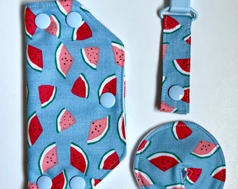 Könnte beinhalten: Ein Set aus drei Baby-Lätzchen mit Wassermelonen-Druck. Die Lätzchen sind aus weichem, blauem Stoff mit weißen Druckknöpfen. Die Lätzchen sind perfekt, um die Kleidung des Babys während der Mahlzeiten sauber zu halten.