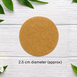 Może przedstawiać: Okrągła tarcza w kolorze opalenizny o teksturowanej powierzchni. Obiekt jest oznaczony tekstem 2.5 cm diameter (approx), wskazującym na jego rozmiar. Tarcza ma płaski, jednolity wygląd i sp&oacute;jny jasnobrązowy kolor na całej swojej powierzchni.