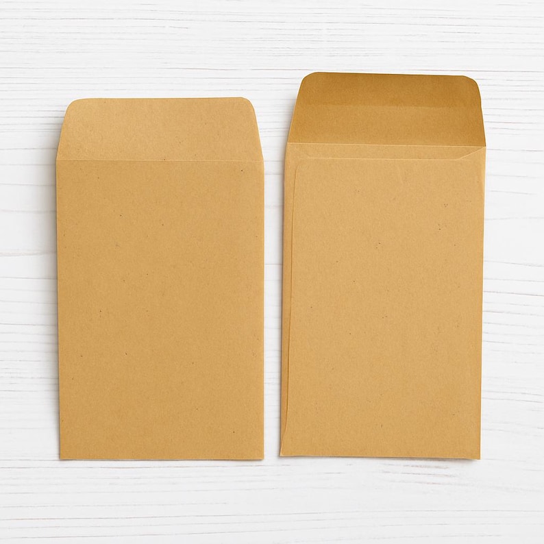 Puede incluir: Dos sobres rectangulares hechos de papel kraft de color marr&oacute;n claro. Un sobre se muestra con la solapa doblada hacia abajo, mientras que el otro sobre est&aacute; colocado con la solapa abierta, revelando la construcci&oacute;n interior de la papeler&iacute;a.