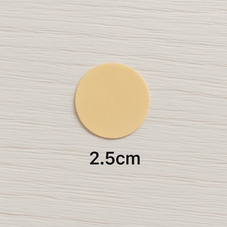 Puede incluir: Un disco circular de color amarillo p&aacute;lido s&oacute;lido con un acabado mate y liso. El objeto est&aacute; colocado sobre el texto 2.5cm, que indica su di&aacute;metro en unidades m&eacute;tricas. El disco es plano y presenta una superficie uniforme de color crema.
