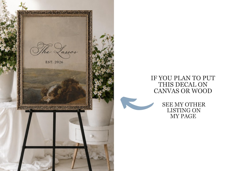 May include: An antique-style framed print on a black easel. The print features a landscape painting with the text "The Lassos EST. 2026". The frame has a gold finish. The image is displayed in a well-lit room with white flowers.