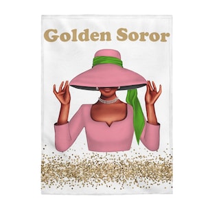 Op de afbeelding: Een witte achtergrond met gouden glitter aan de onderkant. Een vrouw met een bruine huid draagt een roze jurk en een roze hoed met een groen lint. De tekst "Golden Soror" staat bovenaan de afbeelding.