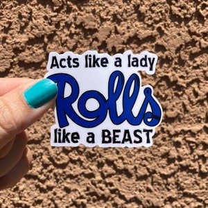 Op de afbeelding: Een witte sticker met blauwe tekst die "Acts like a lady Rolls like a BEAST" zegt.