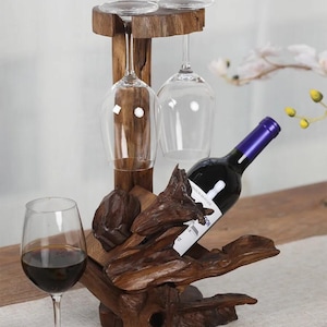 May include: A wooden wine rack with a rustic, natural design. The rack features two glass holders and a space for a bottle of wine. The wine rack is made of dark brown wood with a natural, rough texture.