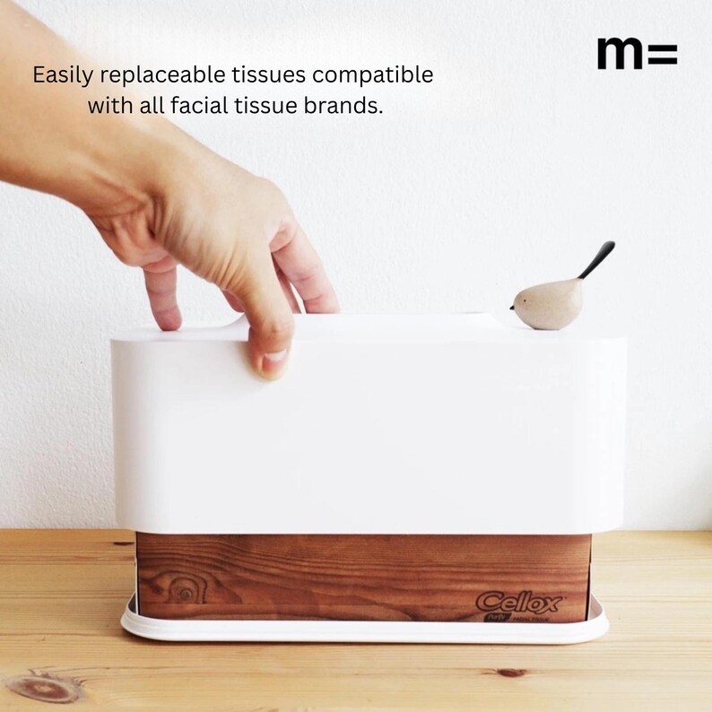 May include: White tissue box holder with a wooden base and a small bird figurine on top. The box is labeled "Cellox" and the holder is labeled "m=".