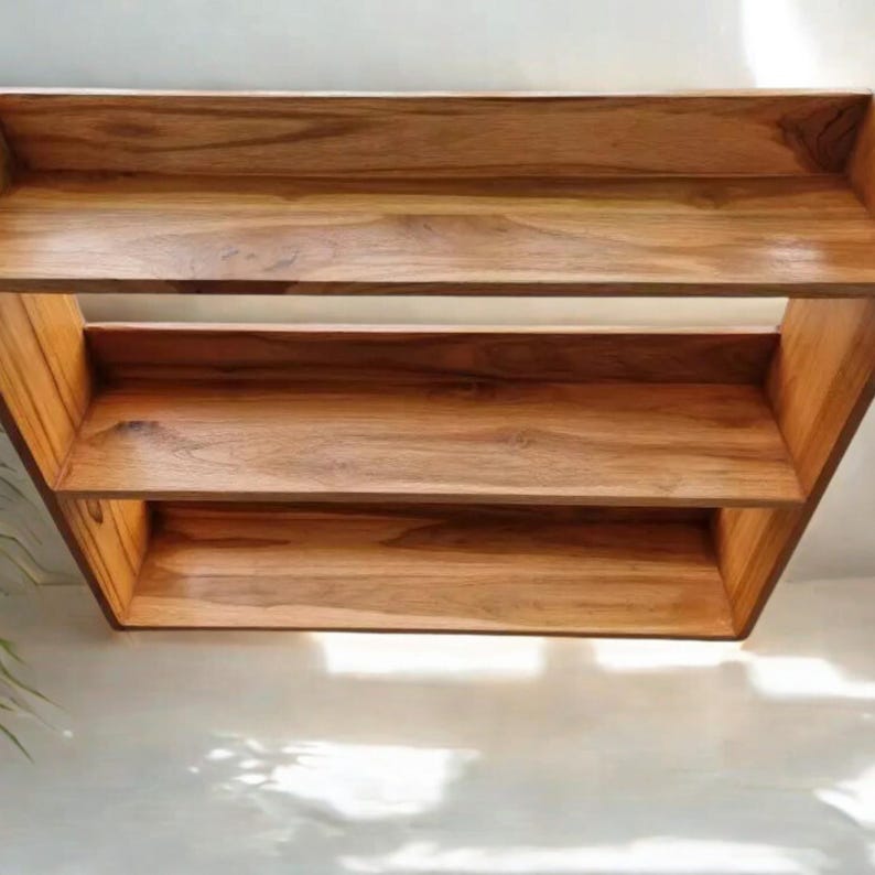 Op de afbeelding: Een houten plankeneenheid met drie niveaus en een natuurlijke houtnerf afwerking. De planken zijn rechthoekig en lijken te zweven, met een eenvoudig, modern ontwerp. De eenheid is waarschijnlijk voor opslag of weergave.