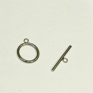 May include: Two silver metal clasps for jewellery making. One is a round ring with a small loop at the top. The other is a straight bar with a small ring at one end.
