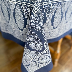 May include: A blue tablecloth with a white paisley pattern. The tablecloth is draped over a wooden table.