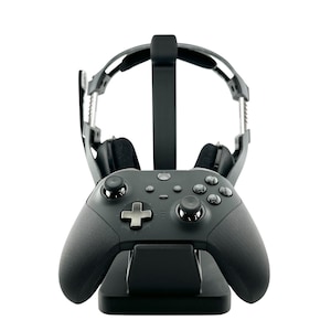 May include: A black gaming controller and headset stand. The stand holds a black controller with a cross-shaped directional pad and two joysticks. A black headset rests on the stand, with the earcups facing forward.