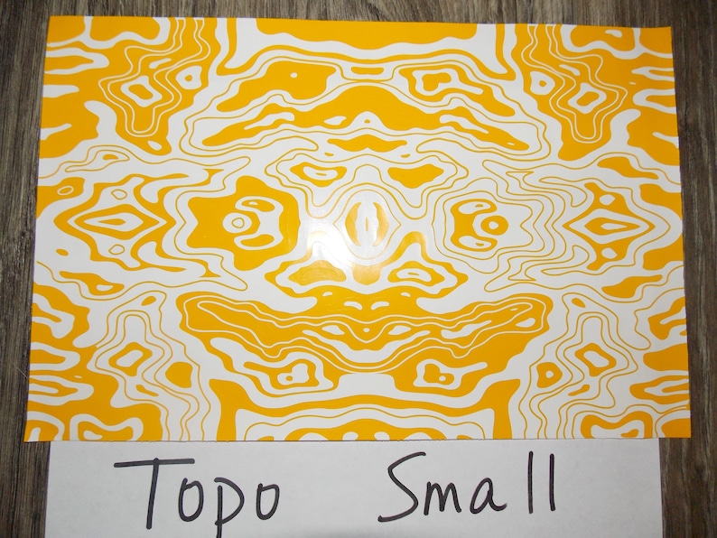 May include: Yellow and white abstract pattern with a topographic design. The text "Topo Small" is written below the pattern.
