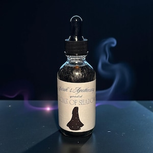 May include: A clear glass bottle with a black liquid and a black dropper. The label reads "Sarah's Apothecary" and "Cloak of Shadow" with a silhouette of a cloak. The background is dark with wisps of smoke.