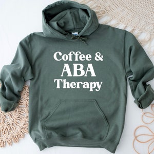 May include: A dark green hooded sweatshirt with the text "Coffee & ABA Therapy" printed in white on the front.