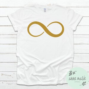 May include: White t-shirt with a gold infinity symbol graphic.
