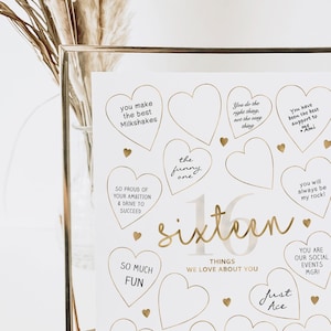 May include: A white framed poster with gold hearts and the text "sixteen" in gold script. The hearts have prompts for writing things people love about the person turning sixteen.