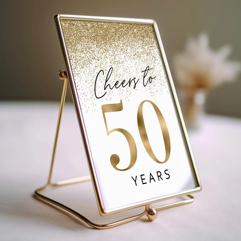 Gold glitter table number card with a gold frame and stand. The poster says "Cheers to 50 Years".