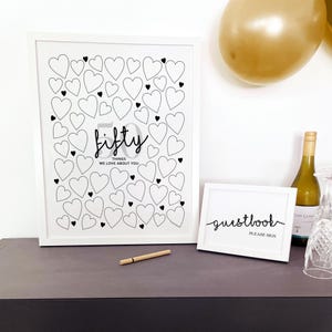 50th Birthday Party Sign In for Guests to write 50 birthday messages in the blank hearts, displayed in white frame with gold balloons, wine, glassware and a small sign that reads Guestbook Please Sign