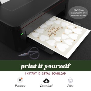 May include: A printable 8x10 inch sign with a beige background and white hearts. The sign says "Our Love Story" in brown text and has small brown hearts scattered around the page. The sign is being printed on a black and silver printer.