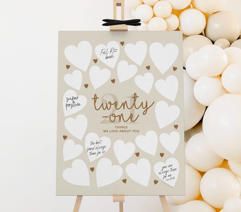 May include: A beige poster with white heart shapes for guests to write on. The poster has the text "twenty-one things we love about you".