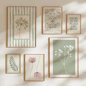 May include: A selection of framed botanical art prints in various sizes. The prints showcase floral and leaf illustrations in soft green, pink, and white tones. One print includes the text "THERE IS NO PLACE LIKE HOME". The frames are a warm wood colour.