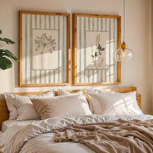 Peut inclure: Deux impressions botaniques encadr&eacute;es avec des fonds &agrave; rayures vert clair et des cadres en bois sont accroch&eacute;es au-dessus d'un lit. Le lit a une literie blanche et une couverture beige. Une grande plante verte est dans le coin.