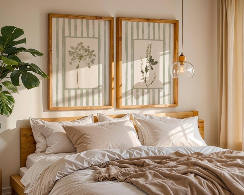 Peut inclure: Deux impressions botaniques encadr&eacute;es avec des fonds &agrave; rayures vert clair et des cadres en bois sont accroch&eacute;es au-dessus d'un lit. Le lit a une literie blanche et une couverture beige. Une grande plante verte est dans le coin.