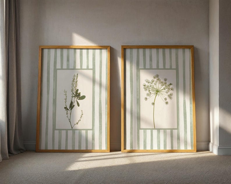 Peut inclure: Deux impressions botaniques encadr&eacute;es. Chacune pr&eacute;sente une illustration de plante dans un cadre rectangulaire, sur un fond de rayures verticales vertes claires et blanches. Les cadres sont de couleur marron clair et chaud.