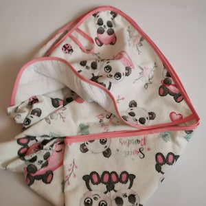 May include: A white hooded towel with a pink trim and a pattern of black and white pandas holding pink hearts. The text "Sweet Pandas" is printed on the towel.