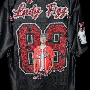 May include: Black baseball jersey featuring the name "Lady Fizz" in red glitter script. The number "88" is in red glitter with a photo of a person in the center. The jersey has a mesh design.