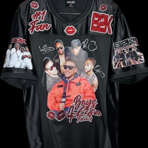 May include: Black mesh jersey with a V-neck, featuring a collage of images and text. Embellishments include red glitter accents and the words "#1 Fan" and "Boys 4 Life Tour". The jersey has images of a musical group.