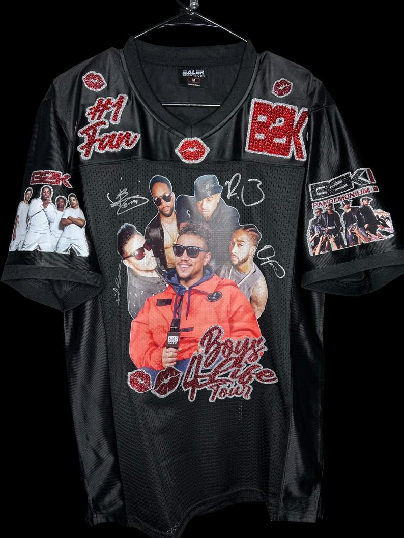 May include: Black mesh jersey with a V-neck, featuring a collage of images and text. Embellishments include red glitter accents and the words "#1 Fan" and "Boys 4 Life Tour". The jersey has images of a musical group.