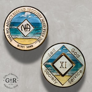 Pode incluir: Dois medalhões redondos de recuperação. Um apresenta uma cena de praia com o texto "THAT NO ADDICT SEEKING RECOVERY NEED EVER DIE..." e "NAWS ©1991". O outro tem "Self, God, Service, Society" e o algarismo romano "XI".