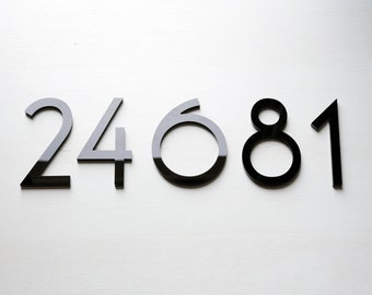 May include: Black acrylic house numbers, 24681, are displayed on a white wall.